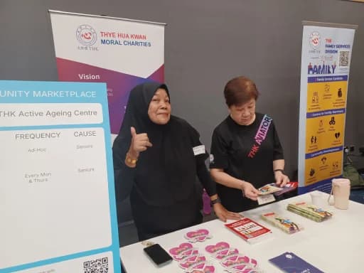 Two THKMC team members hosting a community booth with outreach materials.