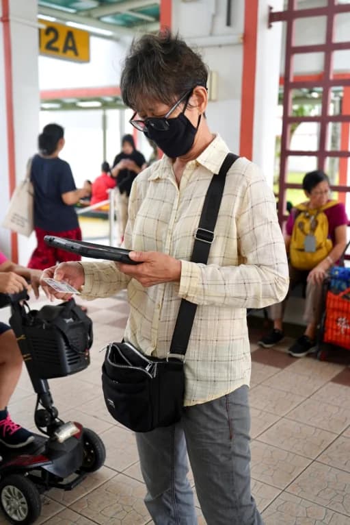 A senior using a tablet with staff support during a community activity.