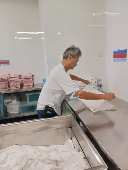 A volunteer folding laundry linens in a THKMC care facility.